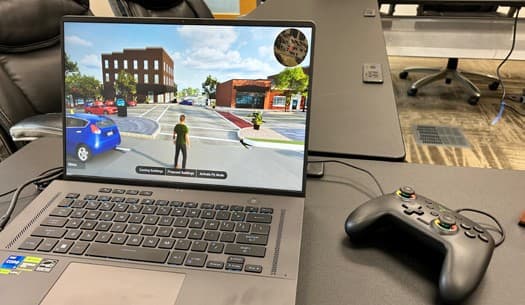 The digital twin running on a laptop in third-person view, with a game controller beside it